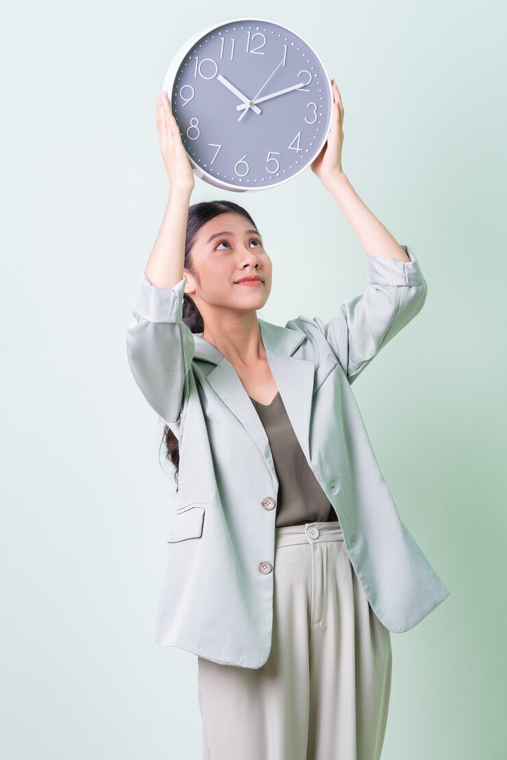 Photo 녹색 배경에 시계를 들고 젊은 아시아 사업가