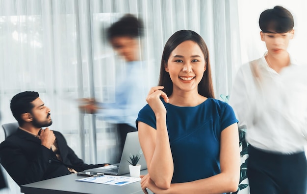 Young Asian businesswoman portrait poses confidently with diverse coworkers in busy meeting room in motion blurred background Multicultural team works together for business success Concord