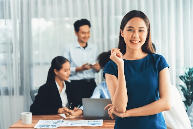 Young Asian businesswoman poses confidently in busy meeting room Concord