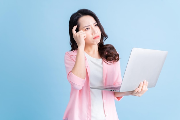 Young Asian businesswoman using laptop on background