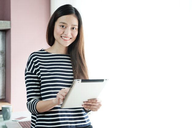 사무실에서 웃는 얼굴로 태블릿을 사용하는 젊은 아시아 사업가