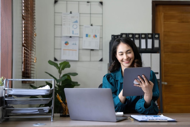 Young asian businesswoman works on tablet with laptop at the office