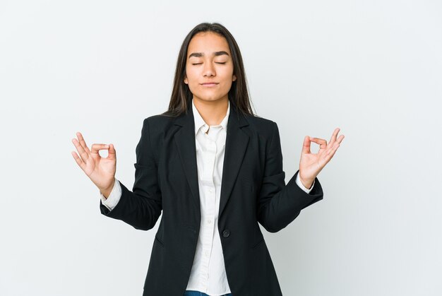 Young asian bussines woman isolated on white wall relaxes after hard working day, she is performing yoga.