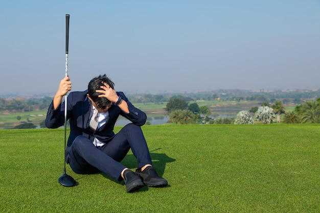 Молодой азиатский генеральный директор бизнесмен в люксе, играя в гольф на поле для гольфа