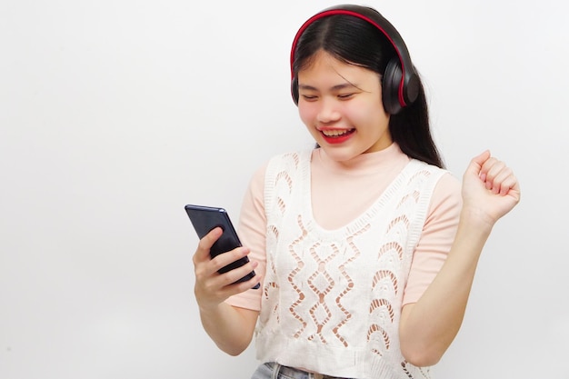 音楽を聴き、スマートフォンを使って楽しむアジアの若い陽気な女性。ライフ スタイルのコンセプトです。