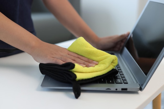 Young Asian cleaning woman uses a towel to clean a computer using cleaning solution in her home office