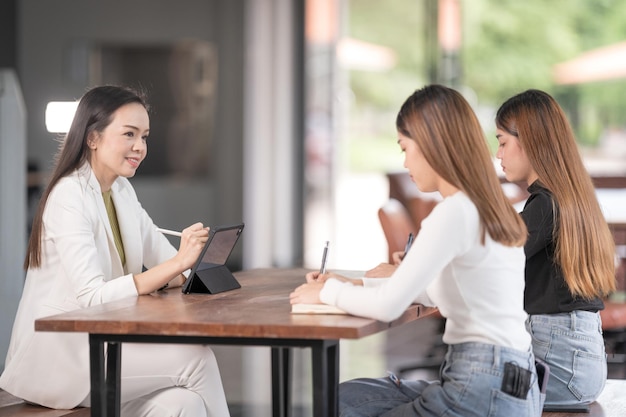 Young Asian college students have meeting with teacher advisor or tutor to discuss project