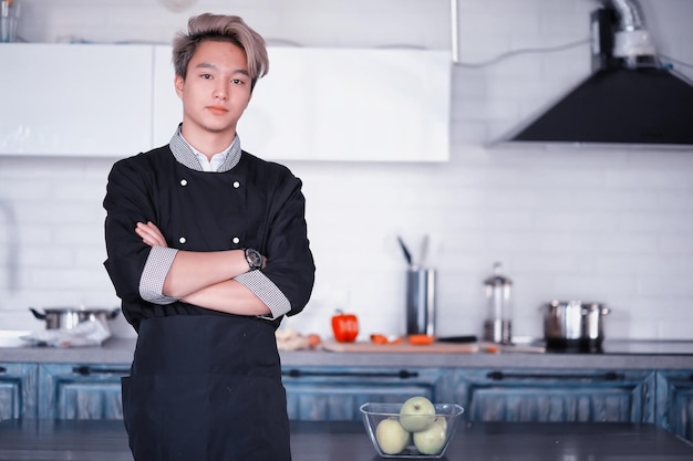 A young Asian cook in the kitchen prepares food in a cook suit