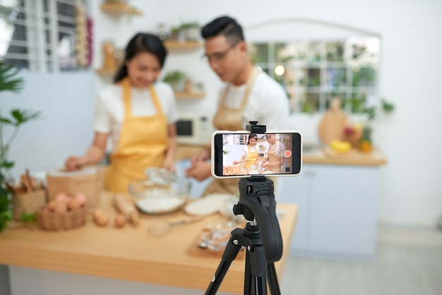 Young asian couple cooking together and recording live video for vlog and social media with professional camera