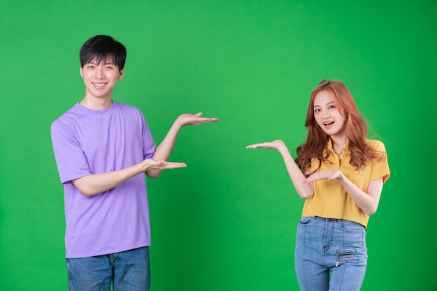 Young Asian couple posing on green background