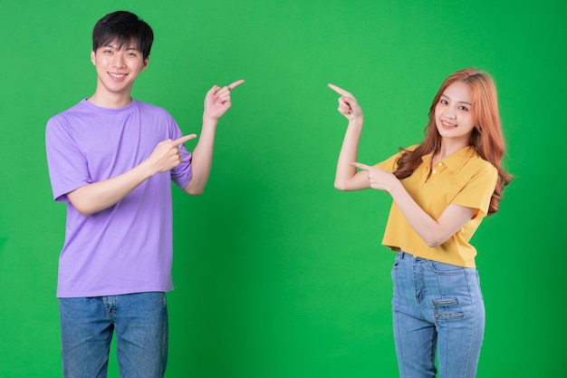 Молодая азиатская пара позирует на зеленом фоне