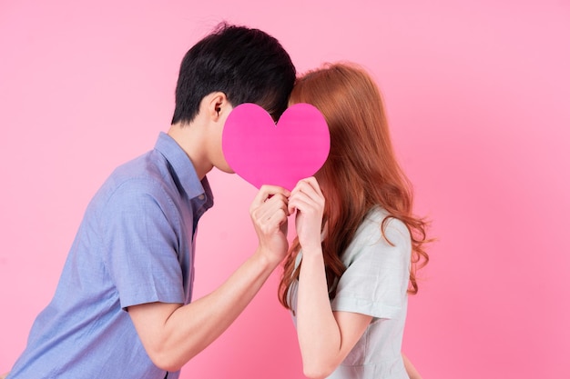 Young Asian couple posing on pink background