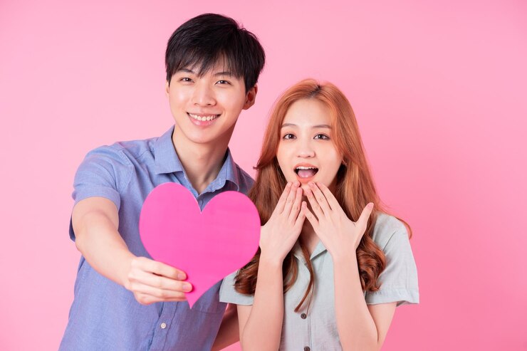 Photo 분홍색 배경에 포즈를 취하는 젊은 아시아 커플