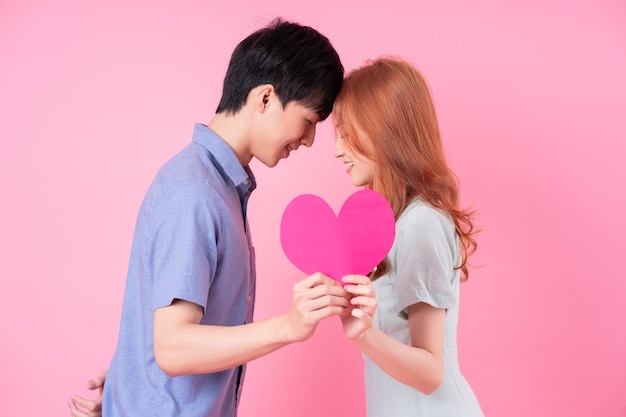 Young Asian couple posing on pink background