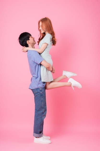 Young Asian couple posing on pink background