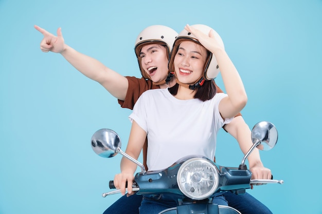 Young Asian couple ride scooter on background