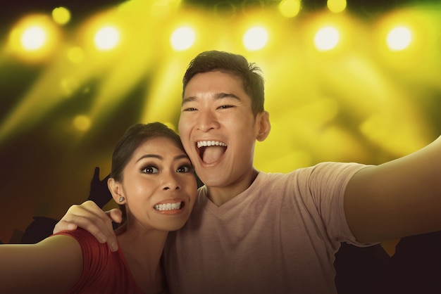 군중과 젊은 아시아 부부 selfie