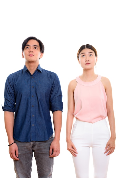 young Asian couple standing while looking up isolated