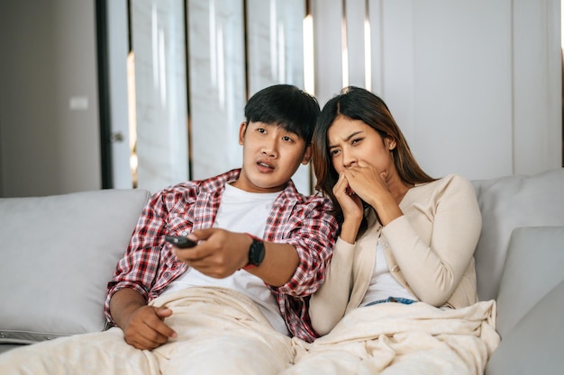 Young Asian Couple watching scary movie on TV at home