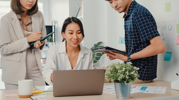 Il giovane uomo d'affari creativo asiatico e il capo manager della donna di affari parlano spiegano la relazione del progetto sul laptop