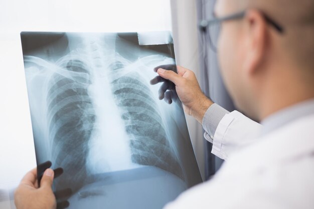 Young asian doctor working from home looking xray film The patients symptoms from the Xray and the results are reported online via video conferencing