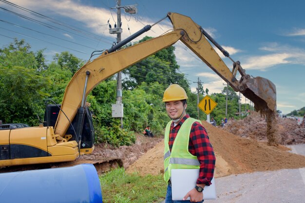 A young Asian engineer is inspecting a large sewer at the construction site.