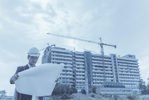 Young asian engineer looking paper plan of the building