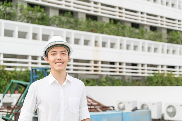 Young Asian engineer with white safety hard helmet 