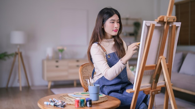 写真 キャンバスの上でクリエイティブな芸術作品を作るために絵を描く若いアジアの女性アーティスト