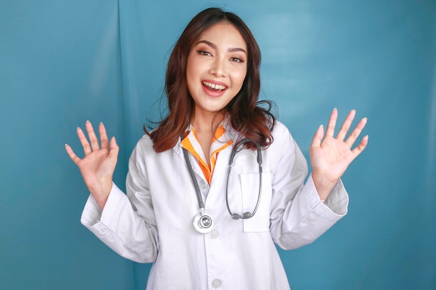 A young Asian female doctor is smiling and giving greeting gesture