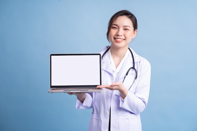 Young Asian female doctor standing on blue background