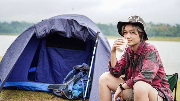 若いアジアの女性が椅子でコーヒーを飲む