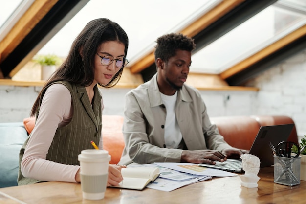 Young asian female economist working with documents and making notes