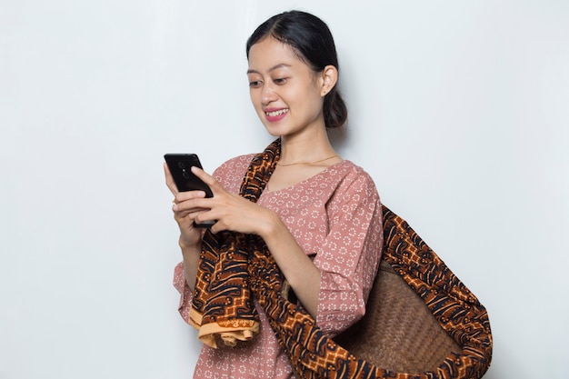 白い背景の上の携帯電話を使用して若いアジアの女性農家
