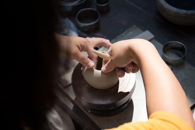 Молодая азиатка сосредотачивается на своей работе в гончарной мастерской