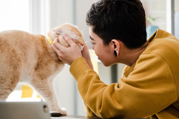 Giovane femmina asiatica felicemente toccando e guardando il suo gatto