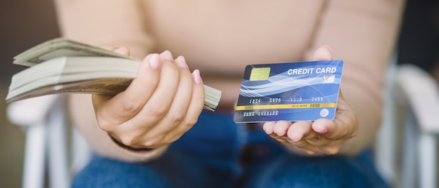 Young asian female is deciding between paying with credit card or cash in coffee shop