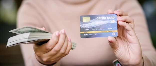 Young asian female is deciding between paying with credit card or cash in coffee shop