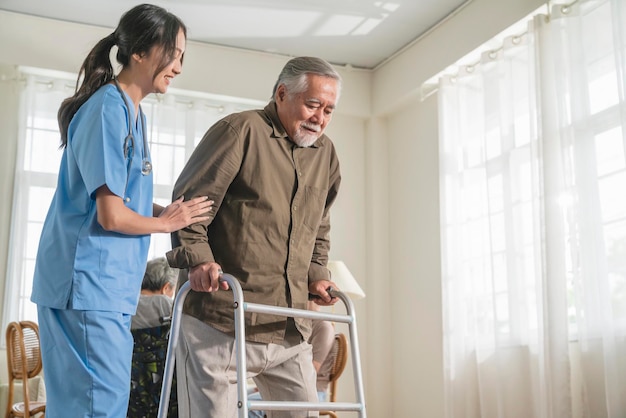 young asian female nurse care giver helping asian senior old man with mobility walker in living area of nursing home senior daycare centernurse take care elderly patient with cheerful concentrate