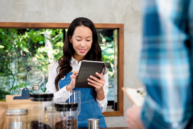 Young Asian female staff taking order from customer in coffee shop