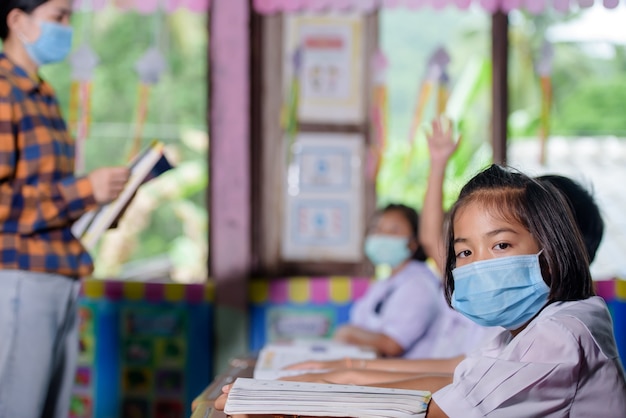 La giovane insegnante femminile asiatica che porta un fronte medico e gli studenti in una scuola di villaggio tailandese rurale stanno imparando