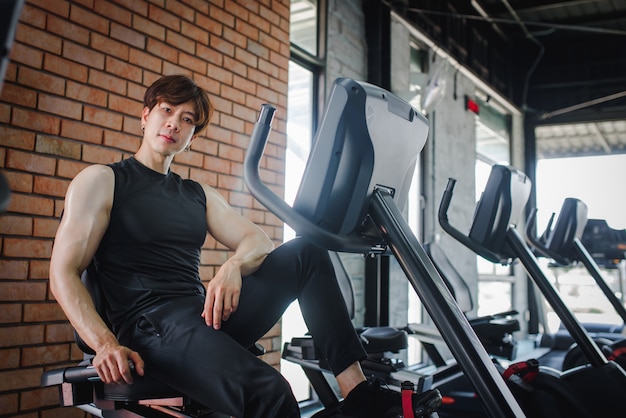 A young Asian fitness trainer sitting at a gym