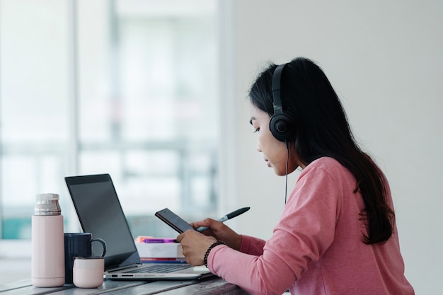 A young Asian freelance businesswoman working  on laptop at home during COVID-19  pandemic.. An adult learner studying online at homet. Stock photo