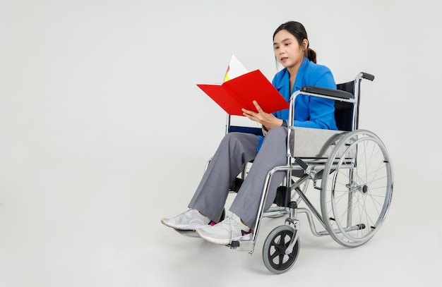 Young Asian girl as disability patient on hospital wheelchair study clinical report by reading physical health care and medical rehabilitation instruction for transporting injured or ill person.