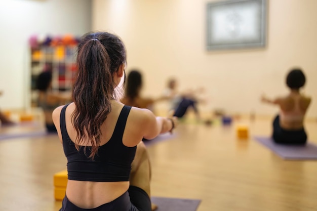 Foto giovane ragazza asiatica che fa yoga insieme ad altre persone