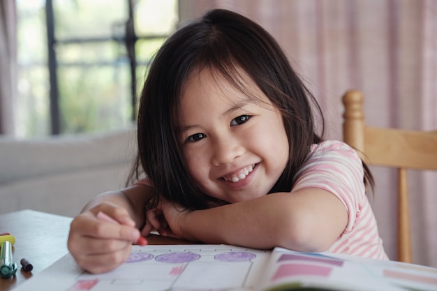 若いアジア人の女の子、家庭で描く、ホームスクールの教育