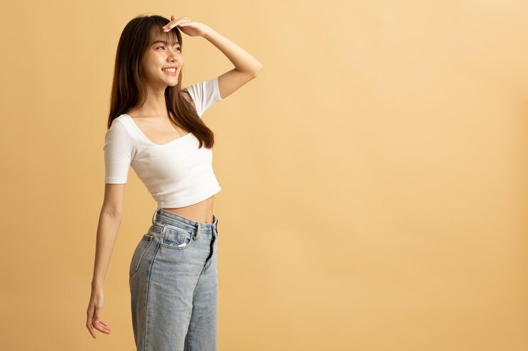Photo 白いシャツとジーンズを着たアジアの若い女の子が黄色い背景で休暇を過ごす準備をしています