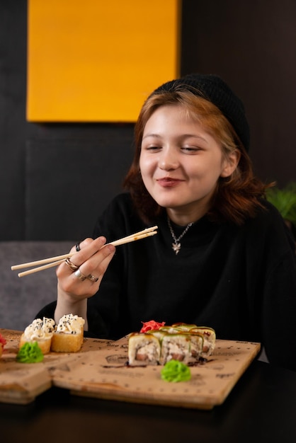 若いアジアの女の子は寿司を食べる