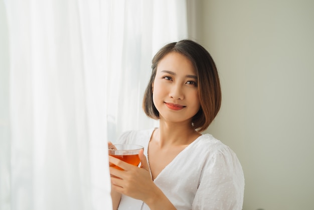 Giovane ragazza asiatica che si sente felice con la sua tazza