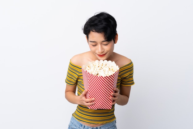 Giovane ragazza asiatica che tiene un grande secchio di popcorn